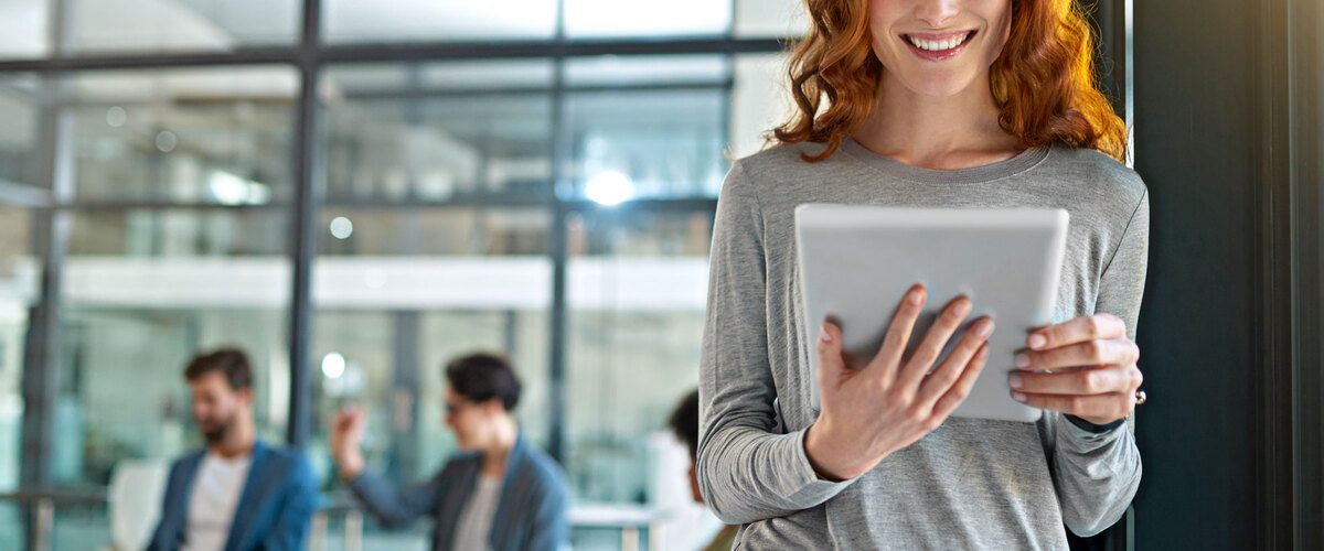 ragazza sorridente con tablet in mano in ufficio