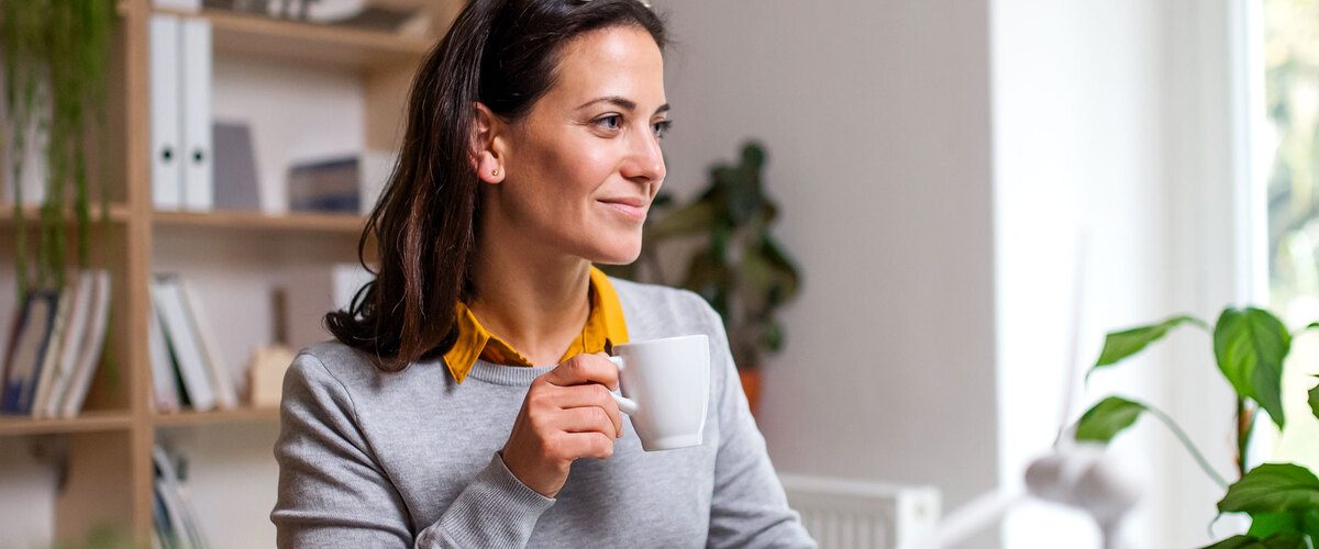 donna davanti al computer che beve una tazza di caffè